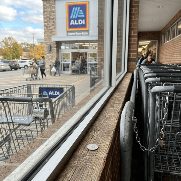 Aldi store entrance with shoppers, shopping carts, and Open 9am-8pm sign